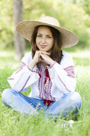Slav teen girl at green meadow in national ukrainian clothing.