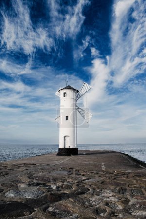 Old lighthouse in Swinoujscie, a port in Poland on the Baltic Sea. The lighthouse was designed as a white traditional windmill.